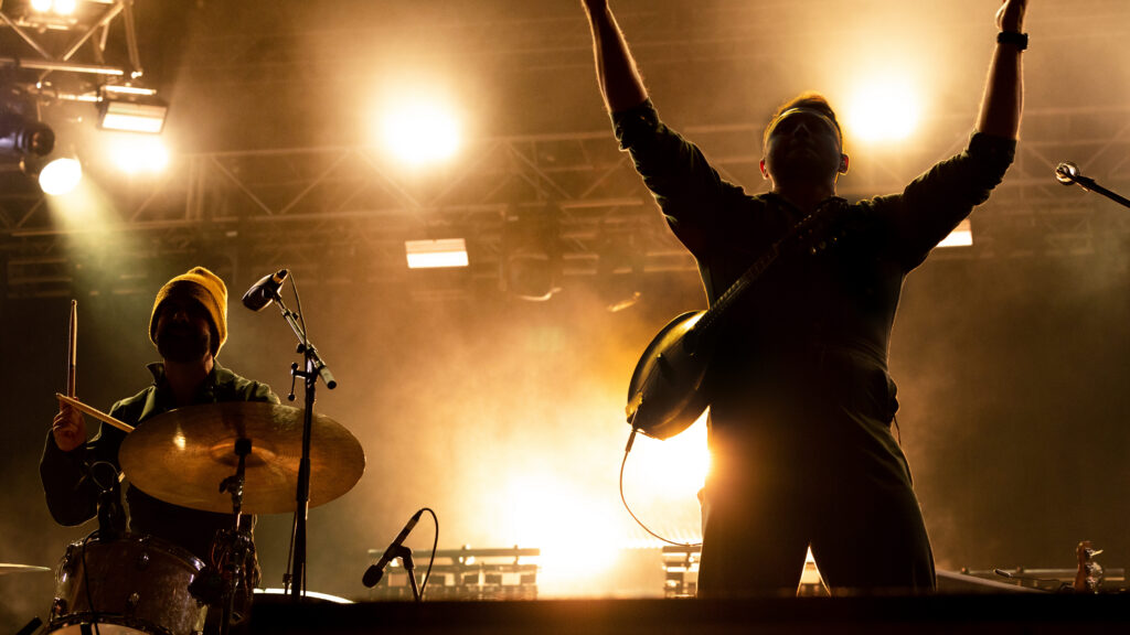 Fan raising an arm under bright stage lights at a Rock the Universe concert at Universal Studios Florida