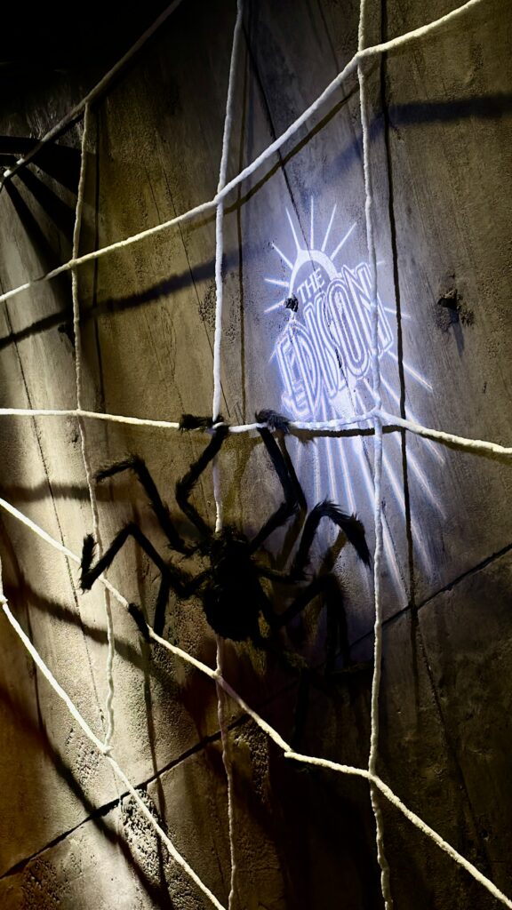 Giant spider and web Halloween decor beside The Edison logo at Disney Springs