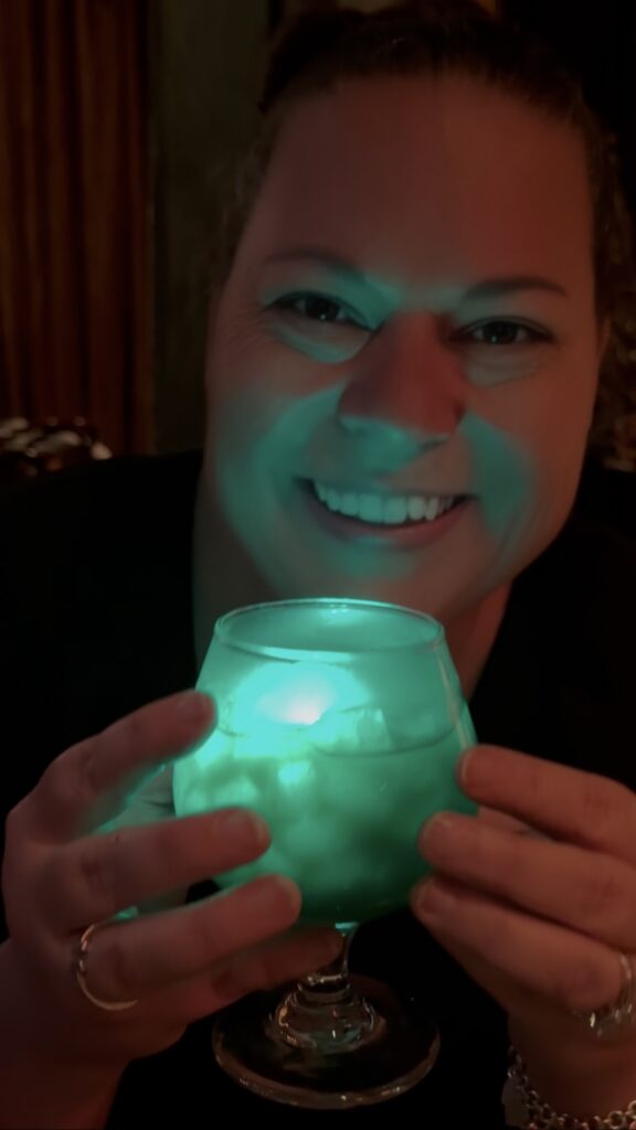 On the Go in MCO holding a glowing green Halloween drink at The Edison, Disney Springs
